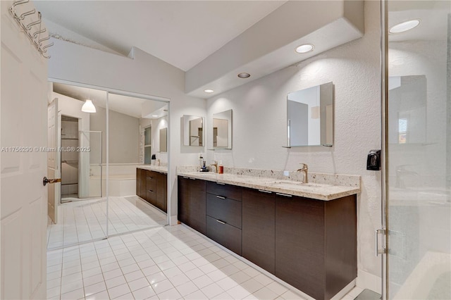 bathroom featuring vaulted ceiling, double vanity, a stall shower, and a sink