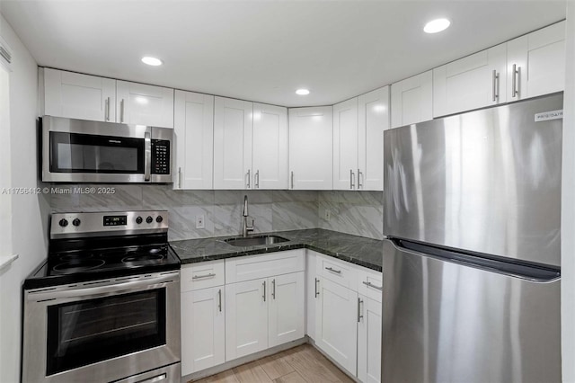 kitchen with tasteful backsplash, white cabinetry, stainless steel appliances, and a sink