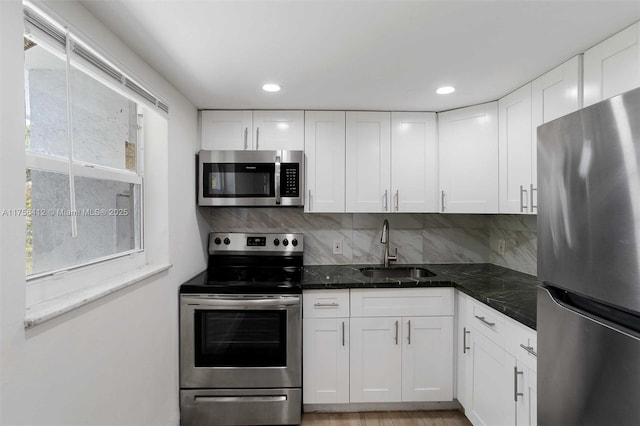 kitchen featuring a sink, white cabinetry, appliances with stainless steel finishes, backsplash, and a wealth of natural light