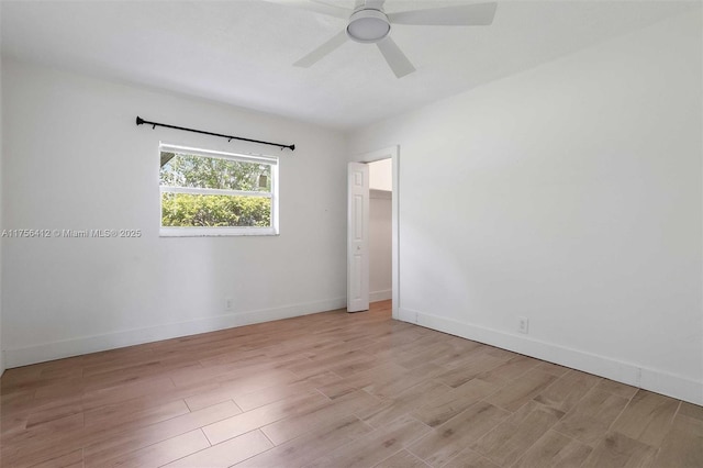 spare room with light wood-type flooring, baseboards, and a ceiling fan