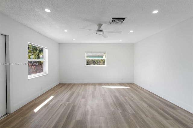 unfurnished room with light wood-style flooring, plenty of natural light, and visible vents