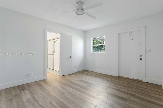 spare room with light wood-style floors, a ceiling fan, baseboards, and a textured ceiling