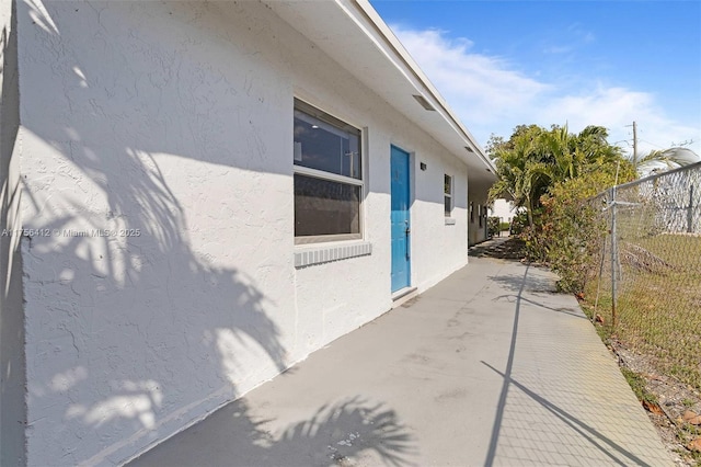 view of property exterior with a patio area, fence, and stucco siding