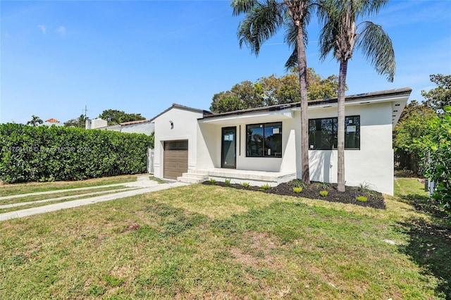 view of front of house featuring a front lawn, a garage, driveway, and stucco siding