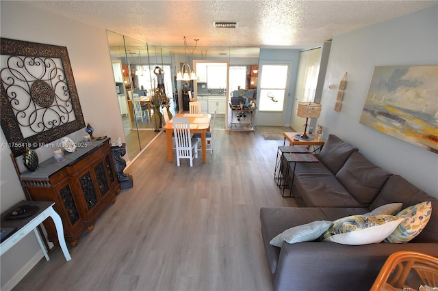 living room featuring a textured ceiling, wood finished floors, and visible vents