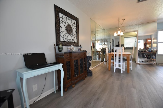 dining area featuring wood finished floors, a textured ceiling, and an inviting chandelier