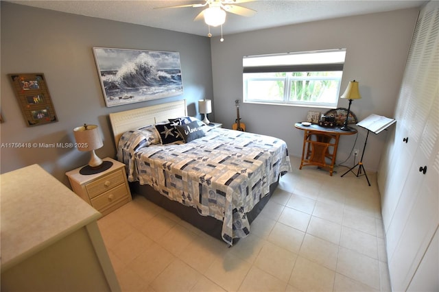 bedroom featuring light tile patterned flooring, ceiling fan, and a textured ceiling