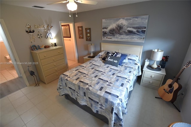 bedroom with light tile patterned floors, ensuite bath, visible vents, and a ceiling fan