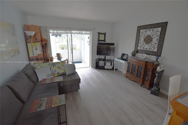 living area with a textured ceiling, baseboards, and wood finished floors