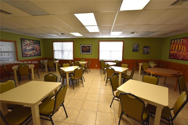 dining space with a wealth of natural light, a drop ceiling, and wainscoting