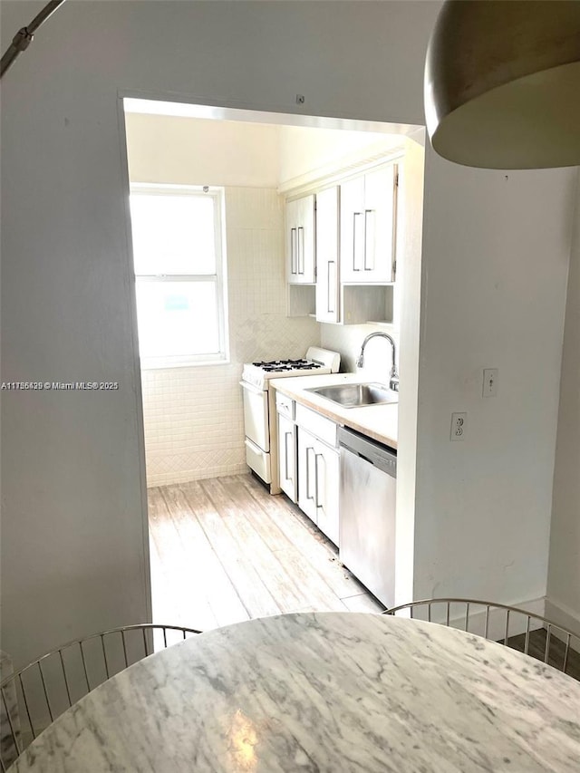 kitchen featuring white cabinetry, dishwasher, white range with gas cooktop, and a sink