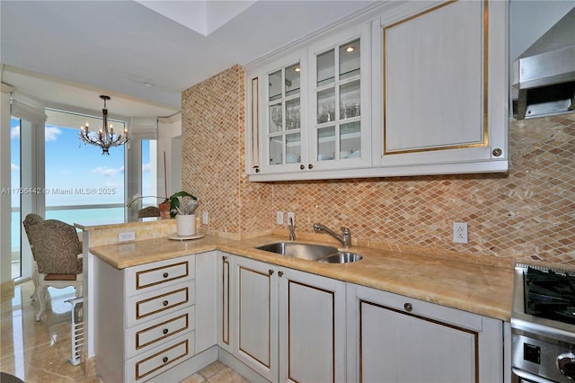 kitchen with light countertops, wall oven, a sink, a peninsula, and wall chimney exhaust hood