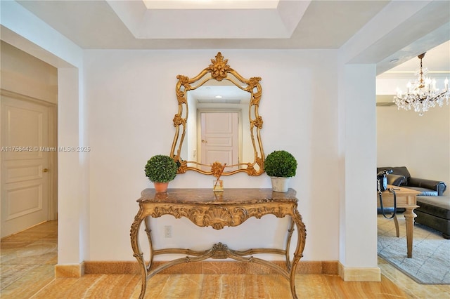 hall featuring baseboards and a chandelier