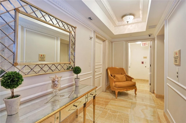 interior space with a tray ceiling, visible vents, crown molding, and a decorative wall