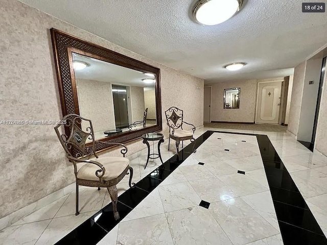 hallway featuring a textured ceiling and marble finish floor