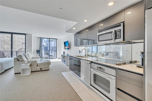 kitchen with stainless steel appliances, light colored carpet, light countertops, a sink, and modern cabinets