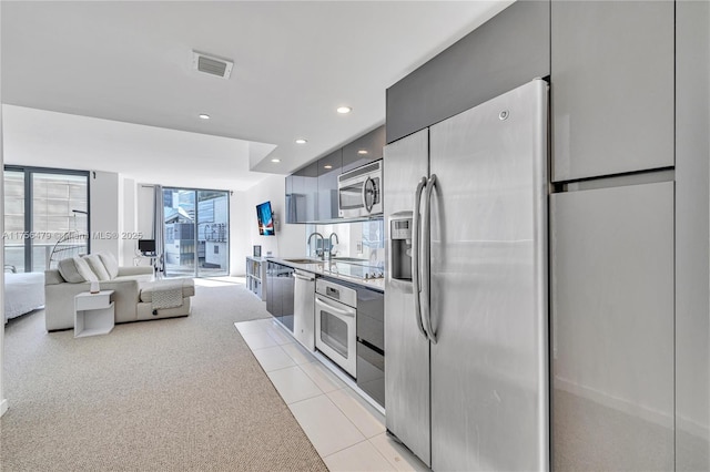 kitchen featuring light tile patterned floors, visible vents, modern cabinets, appliances with stainless steel finishes, and a sink