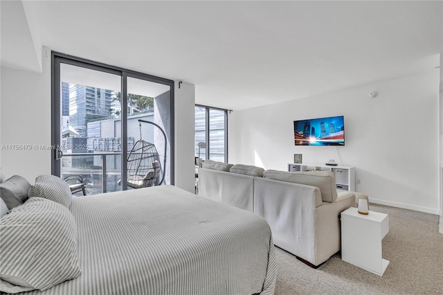 carpeted bedroom featuring access to exterior, baseboards, and a wall of windows