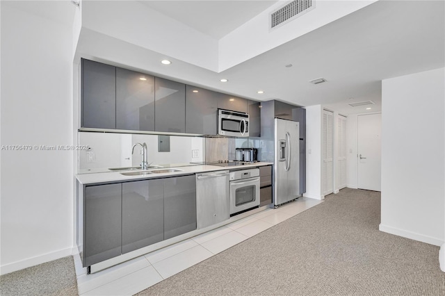 kitchen featuring gray cabinetry, stainless steel appliances, a sink, visible vents, and modern cabinets