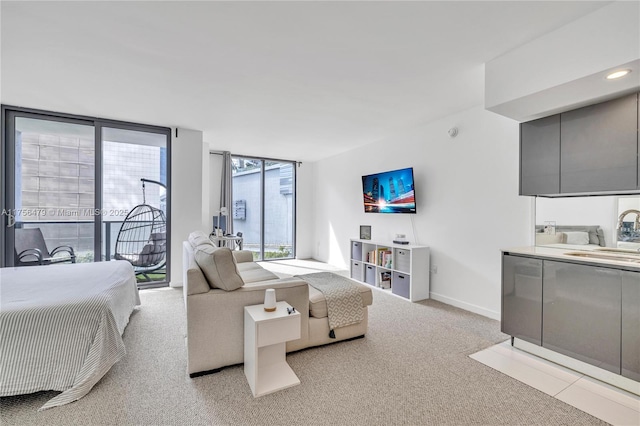 bedroom featuring carpet, floor to ceiling windows, a sink, access to outside, and baseboards