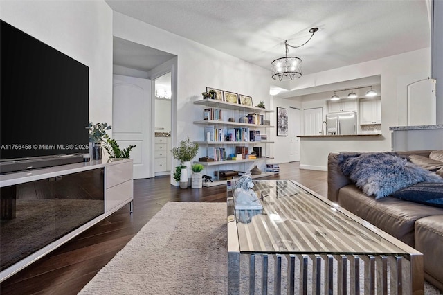 living room featuring an inviting chandelier, baseboards, and wood finished floors