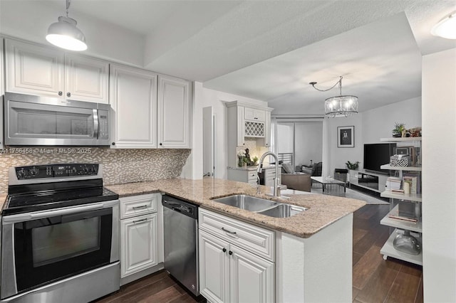 kitchen featuring appliances with stainless steel finishes, dark wood-style flooring, a peninsula, a sink, and backsplash