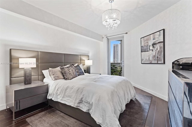 bedroom with a notable chandelier, wood finished floors, and baseboards