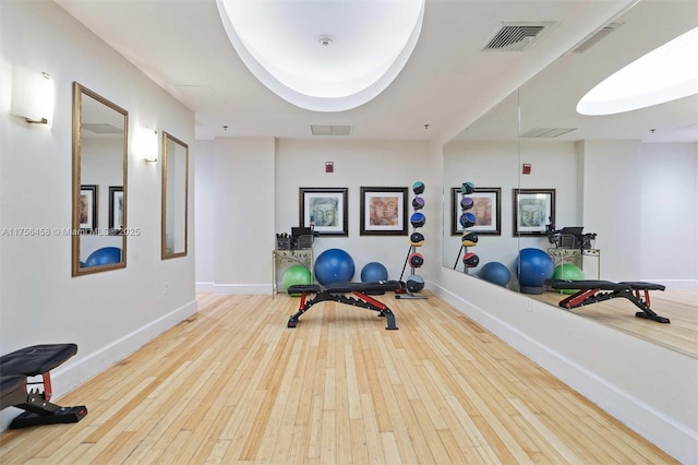 workout room with wood-type flooring, visible vents, and baseboards