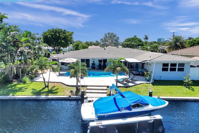 back of house with a patio, a yard, an outdoor pool, a water view, and a tiled roof