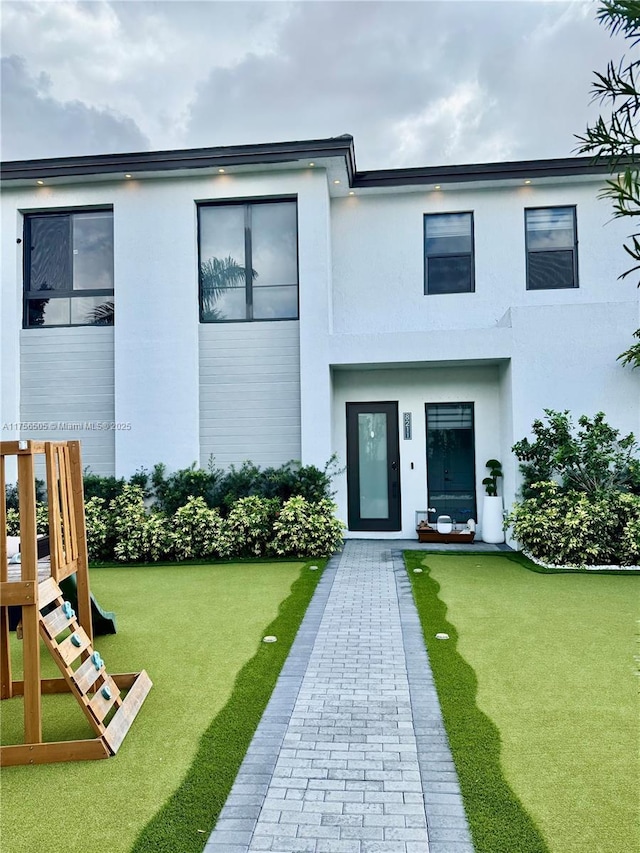 view of front of property featuring a playground and stucco siding