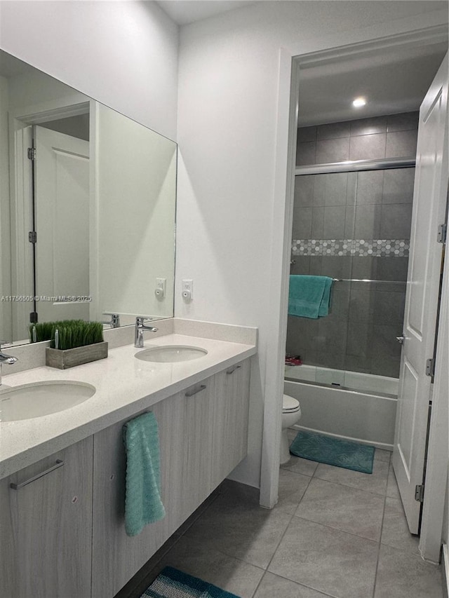 bathroom with toilet, double vanity, a sink, and tile patterned floors