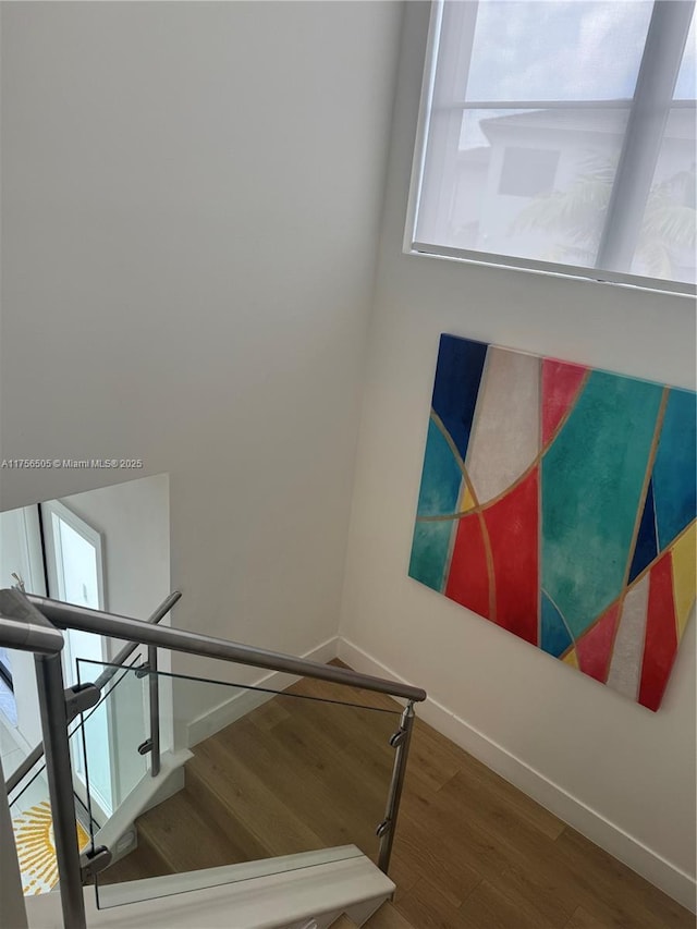 staircase featuring wood finished floors and baseboards