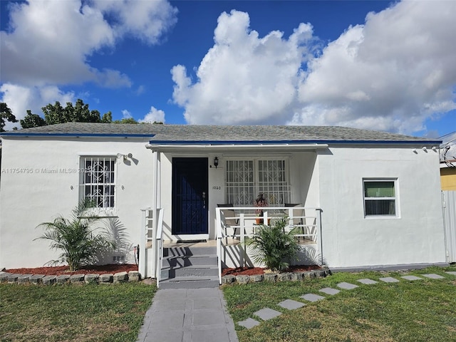 view of front of home with covered porch, stucco siding, and roof with shingles