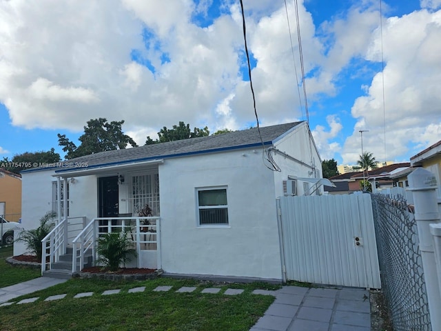 view of front facade featuring a gate, fence, a front lawn, and stucco siding