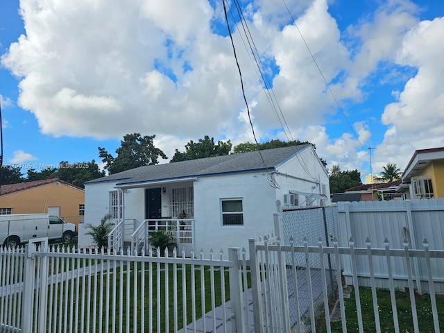 bungalow-style home featuring a fenced front yard, a gate, roof with shingles, and stucco siding