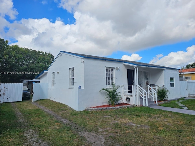 view of front of house with a front yard, fence, a gate, and stucco siding