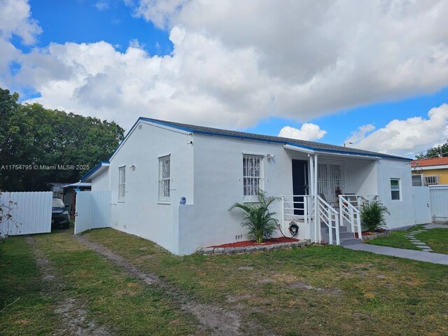 view of front of house with a front yard, fence, a gate, and stucco siding