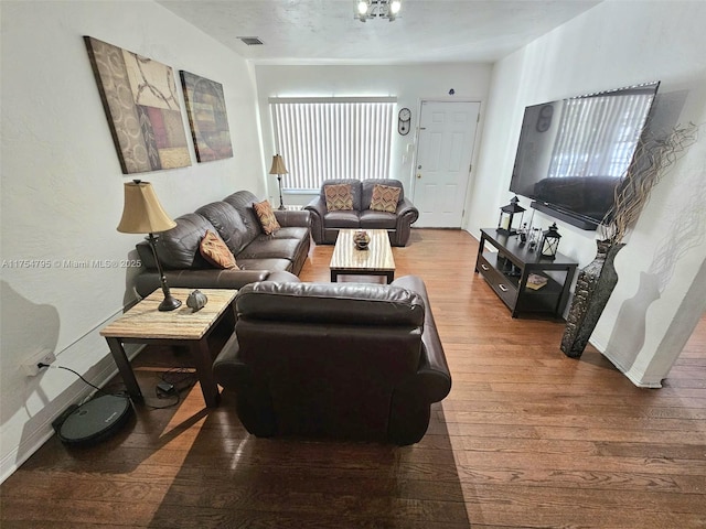 living room featuring wood-type flooring, visible vents, and baseboards