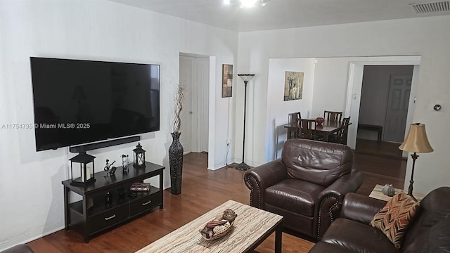 living room with wood finished floors, visible vents, and baseboards