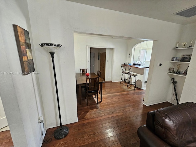 corridor with dark wood-style floors, arched walkways, and visible vents