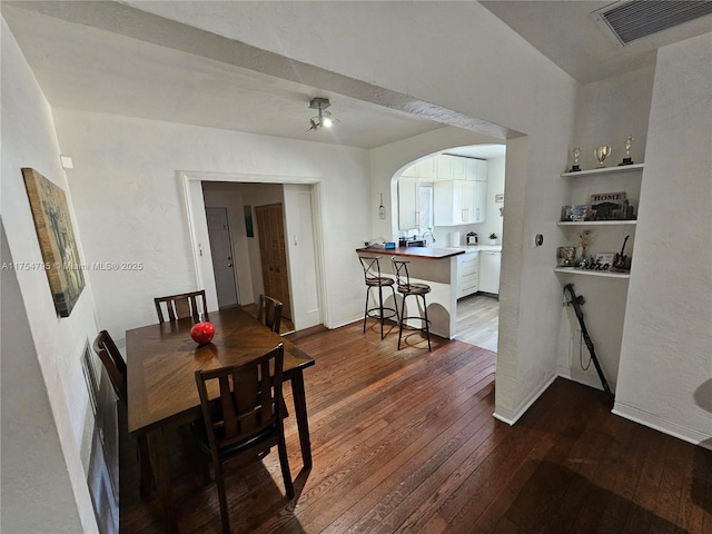 dining space featuring dark wood-style floors, arched walkways, and visible vents