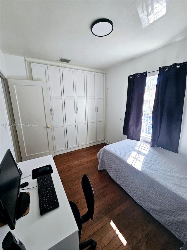 bedroom with visible vents and dark wood-style flooring