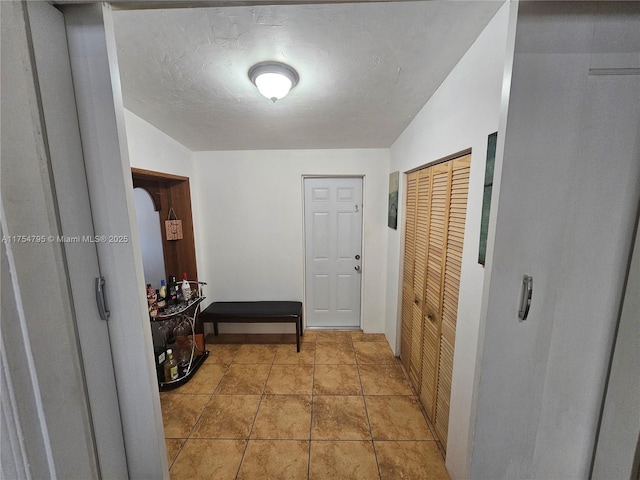 hallway featuring light tile patterned floors and a textured ceiling