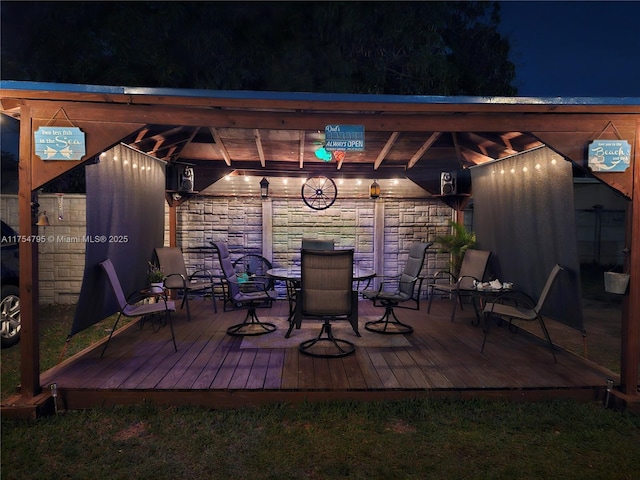 deck at night featuring outdoor dining area