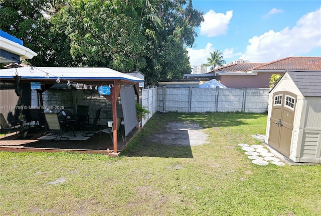 view of yard with a storage shed, a fenced backyard, and an outbuilding