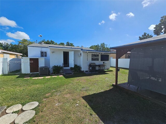 view of front of home with central AC unit, a front yard, fence, and stucco siding