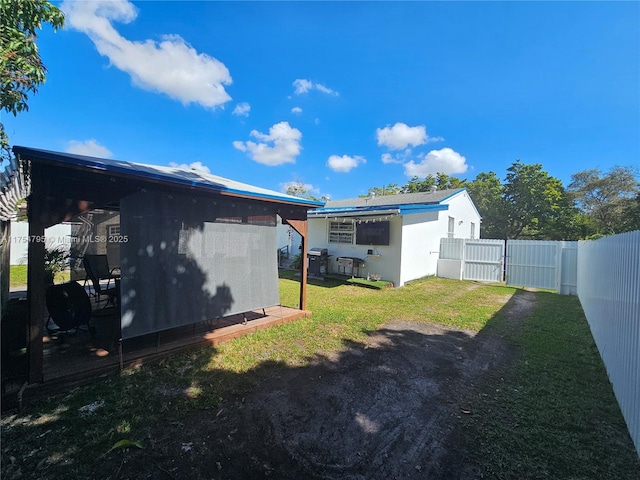 rear view of property featuring a yard, a fenced backyard, and stucco siding