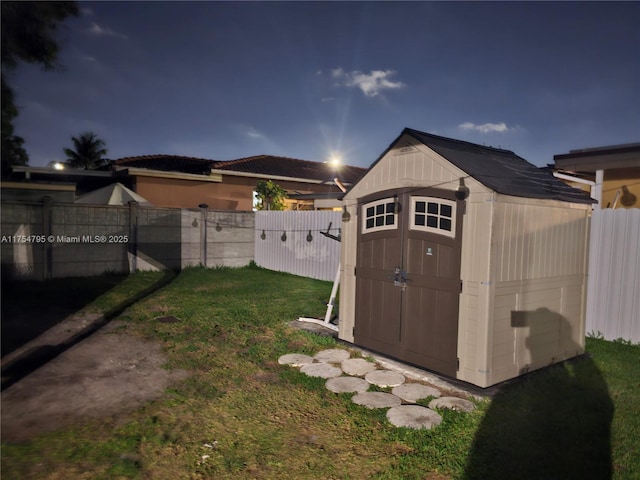 view of yard featuring a fenced backyard, an outdoor structure, and a storage shed