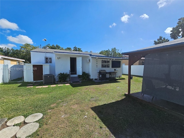 view of front of home featuring fence, a front lawn, cooling unit, and stucco siding