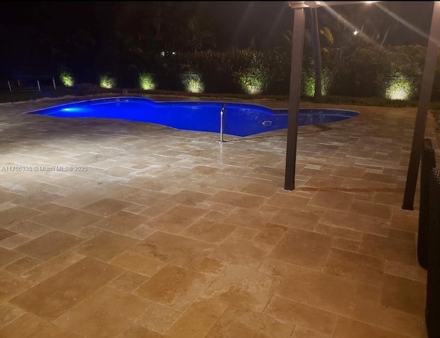 pool at night with a patio and an outdoor pool